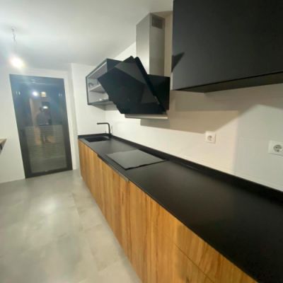 Muebles de cocina en madera de color claro y encimera y muebles de pared oscuros