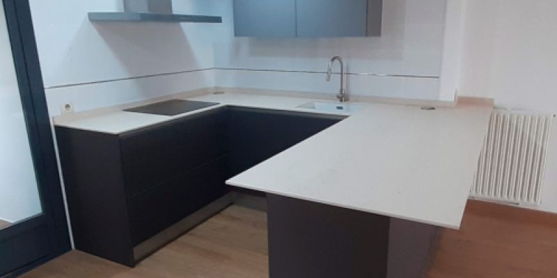 Muebles de cocina de madera oscura y encimera blanca