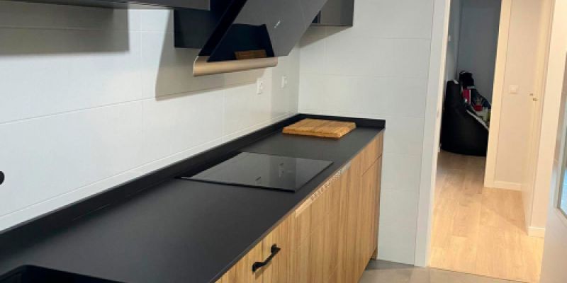 Cocina de madera en color claro con encimera y muebles superiores oscuros