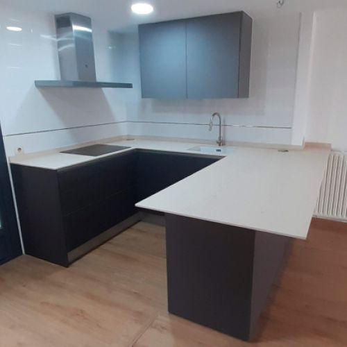 Muebles de cocina de madera oscura y encimera blanca